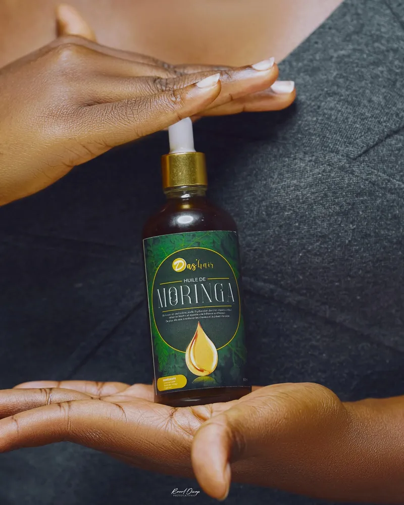 Flacon d'huile de moringa Das'hair tenu entre deux mains